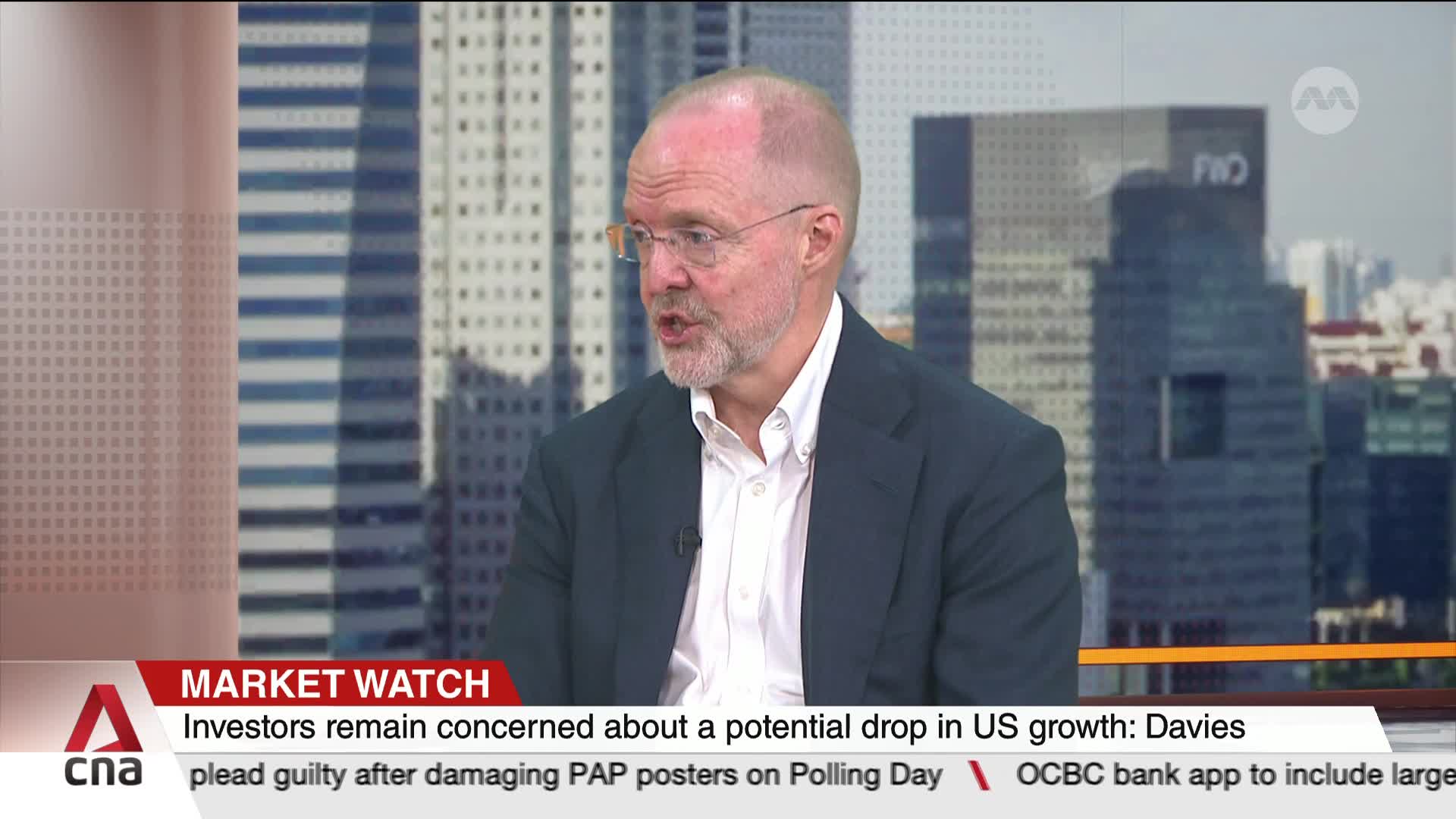 A man in a dark blazer and glasses is speaking, his mouth moving as he gestures. The CNA International logo and "Market Watch" banner are visible at the bottom of the screen.
