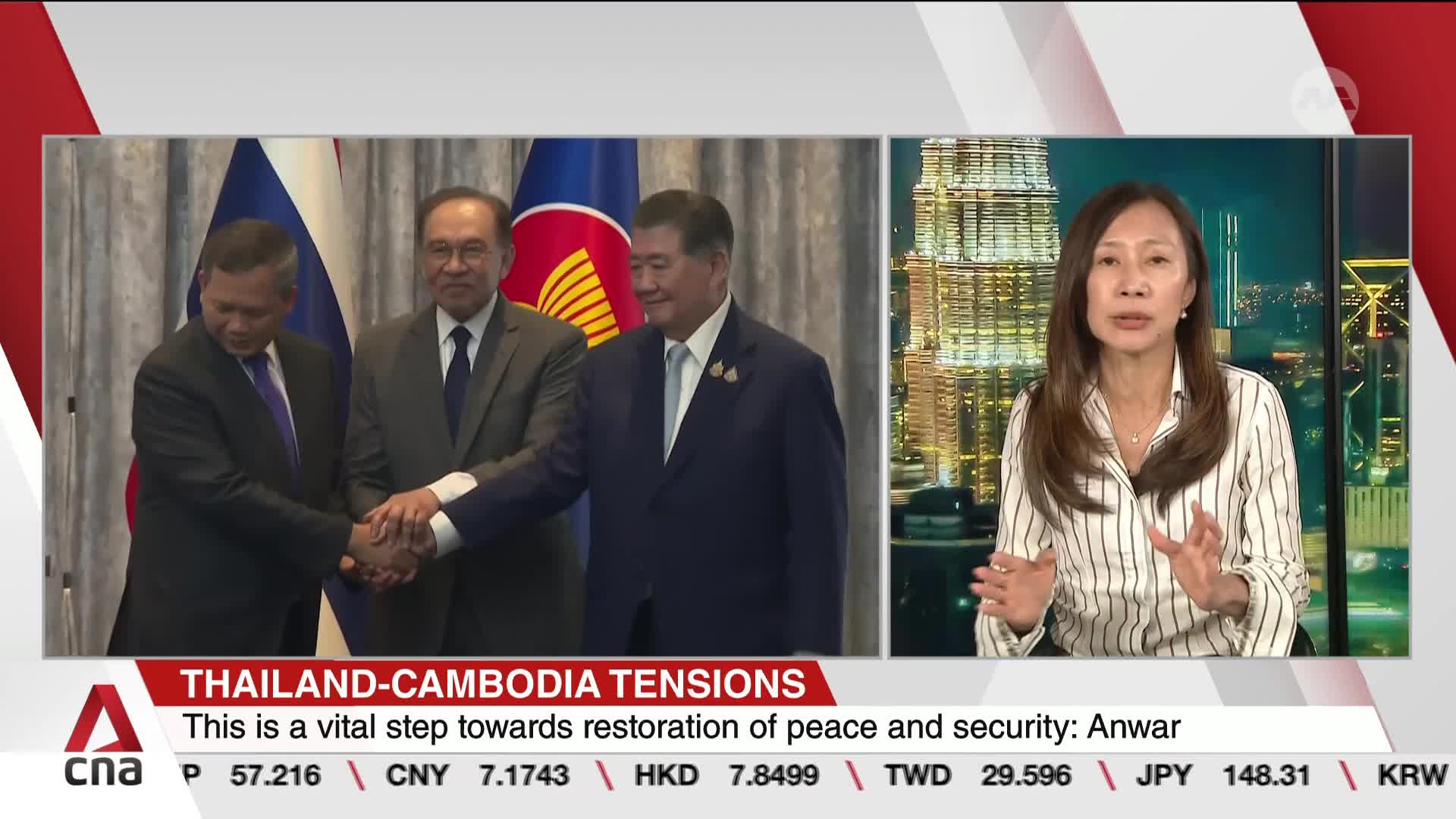 Three men in suits clasp hands in front of flags, while a news anchor from CNA International gestures emphatically. The broadcast from Singapore focuses on tensions between Thailand and Cambodia.

