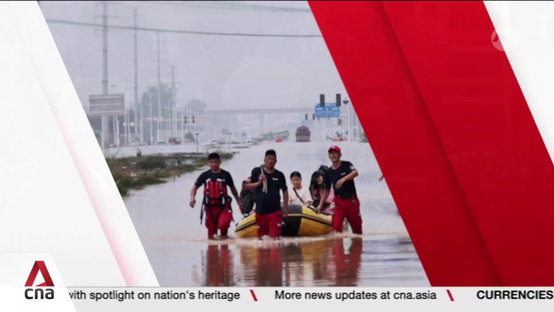 Volunteers, clad in red pants, wade through the flooded street, pulling a yellow raft with several people aboard. Overhead, the sky is overcast, and a bridge looms in the distance, as reported by CNA International.

