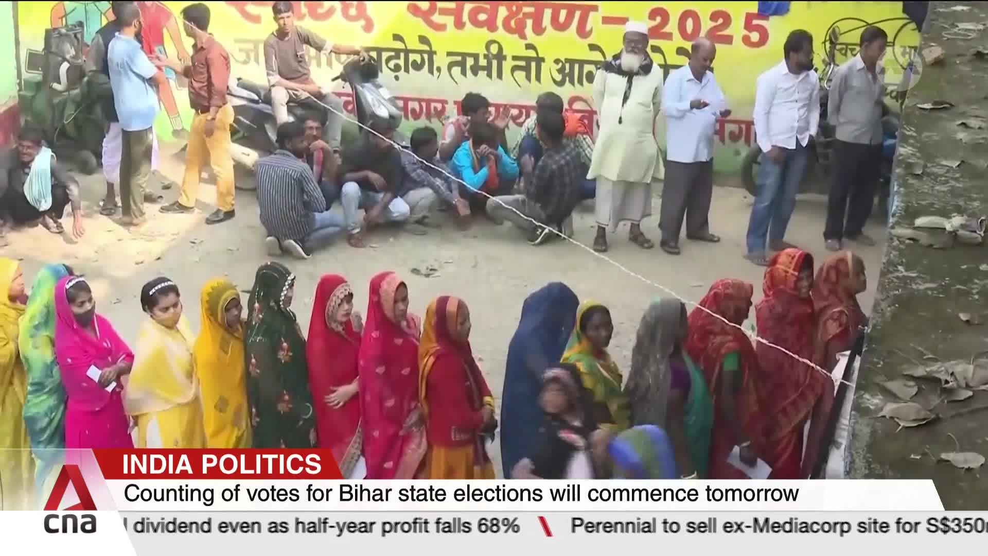 A long queue of women in colorful headscarves stands behind a rope, waiting. Men are gathered nearby, some sitting and others standing, as the CNA International report indicates that vote counting in Bihar is about to begin.
