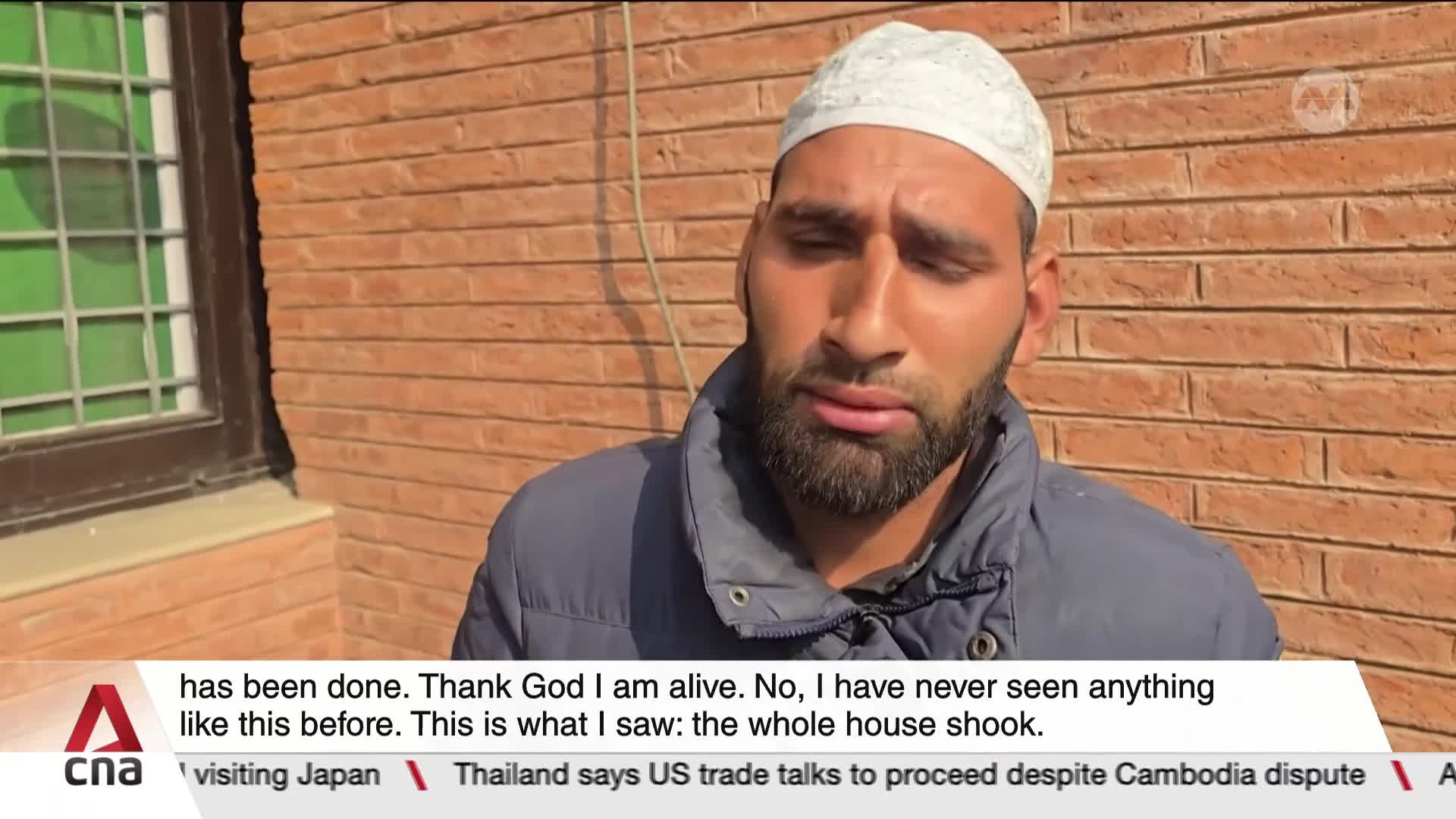 A man in a white cap and jacket is speaking to the camera, his expression somber. The CNA International logo is visible, and the lower third of the screen displays a news headline.
