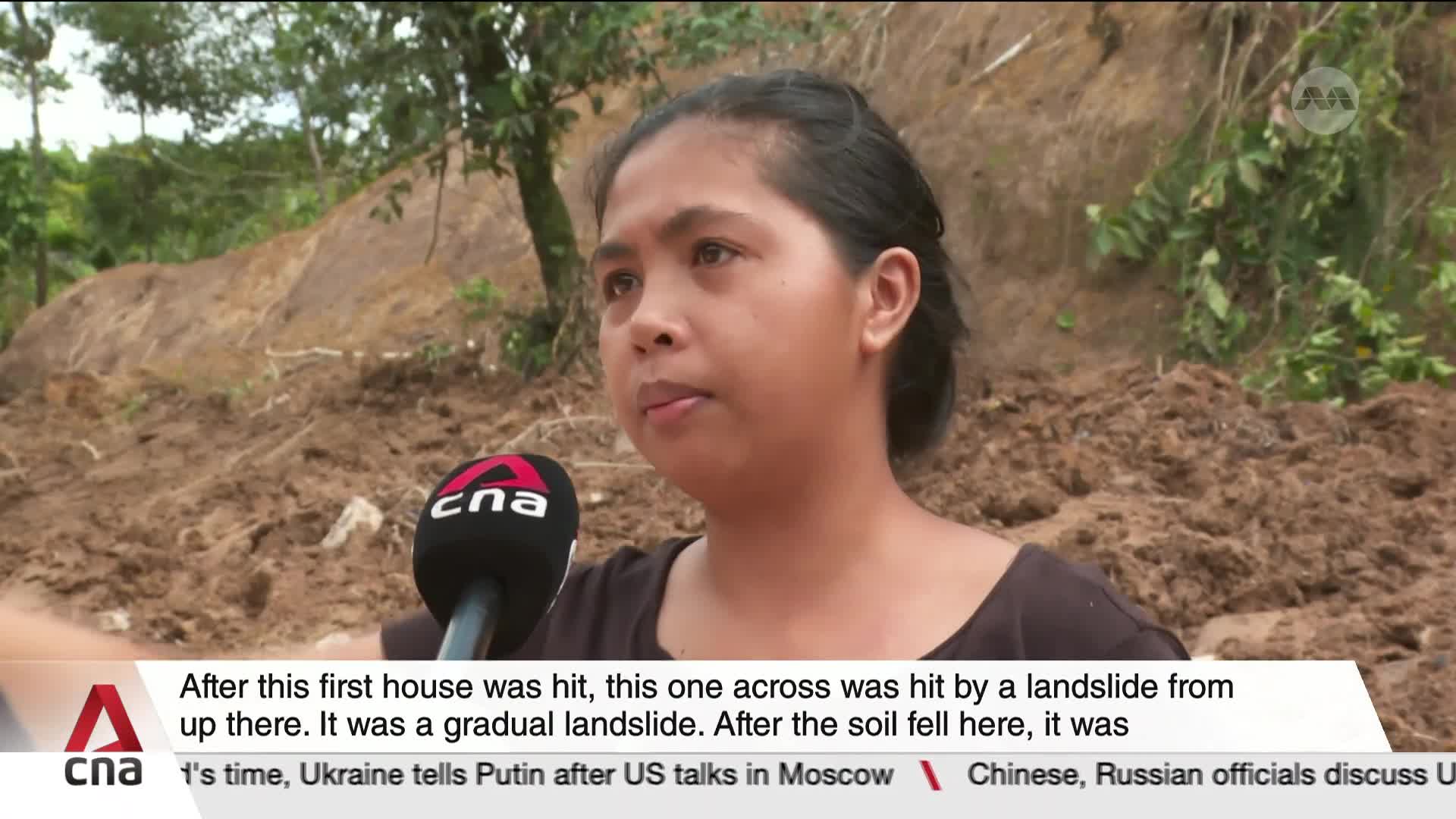 A woman, speaking into a CNA microphone, describes a landslide behind her. The muddy earth covers the hillside, and the news ticker below offers context from Ukraine.
