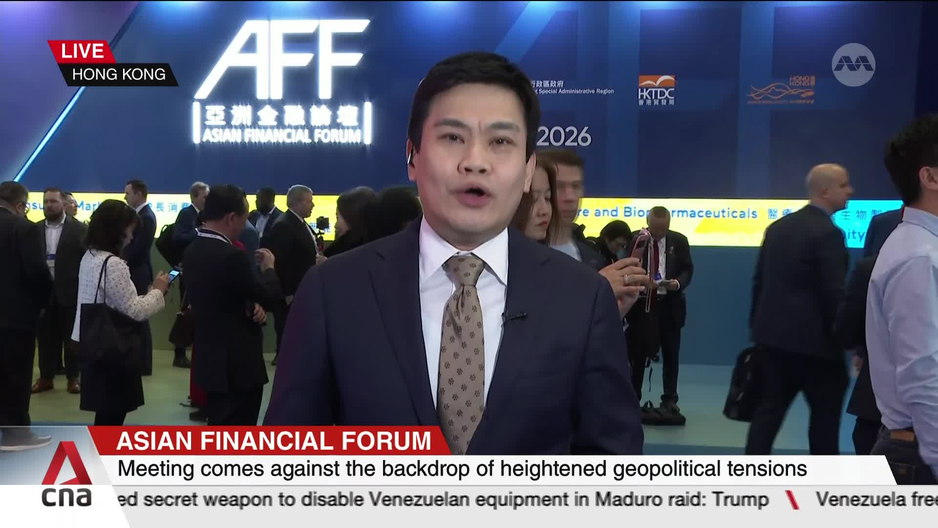 A man in a suit and tie speaks directly to the camera, while attendees mill about behind him at the Asian Financial Forum. The backdrop features the event's logo and the year 2026. A man in a suit and tie speaks directly to the camera, while attendees mill about behind him at the Asian Financial Forum. The backdrop features the event's logo and the year 2026.