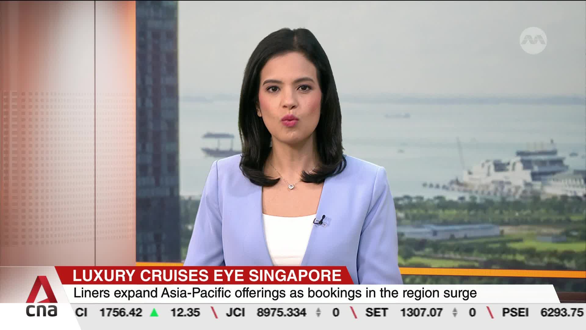 A woman in a light blue blazer speaks directly to me, her words about Singapore's booming cruise industry filling the studio. Behind her, the hazy Singapore skyline features a few boats on the water. A woman in a light blue blazer speaks directly to me, her words about Singapore's booming cruise industry filling the studio. Behind her, the hazy Singapore skyline features a few boats on the water.