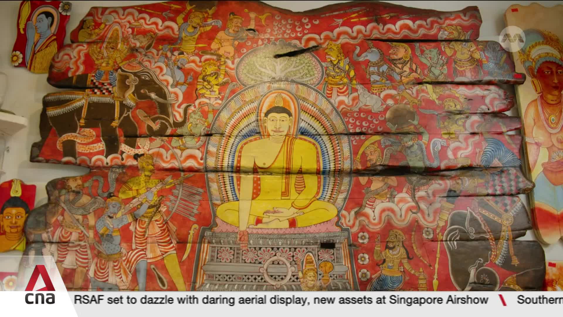 The vibrant, layered artwork depicts a central seated Buddha figure surrounded by scenes of elephants and figures in dynamic poses. The colors are rich, with reds and yellows dominating the composition, all rendered on weathered wooden panels. The vibrant, layered artwork depicts a central seated Buddha figure surrounded by scenes of elephants and figures in dynamic poses. The colors are rich, with reds and yellows dominating the composition, all rendered on weathered wooden panels.