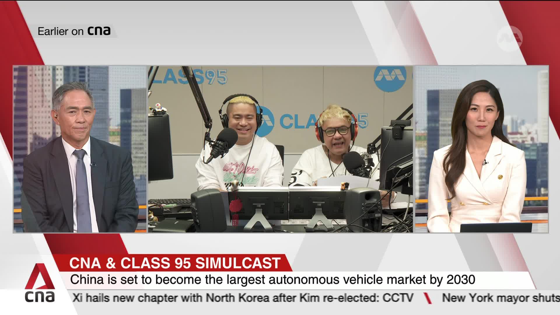 A man in a suit sits on the left, facing the camera. In the center, two men with bright blonde hair laugh into microphones, broadcasting from a studio. To the right, a woman in a cream blazer speaks, her gaze directed forward. A man in a suit sits on the left, facing the camera. In the center, two men with bright blonde hair laugh into microphones, broadcasting from a studio. To the right, a woman in a cream blazer speaks, her gaze directed forward.