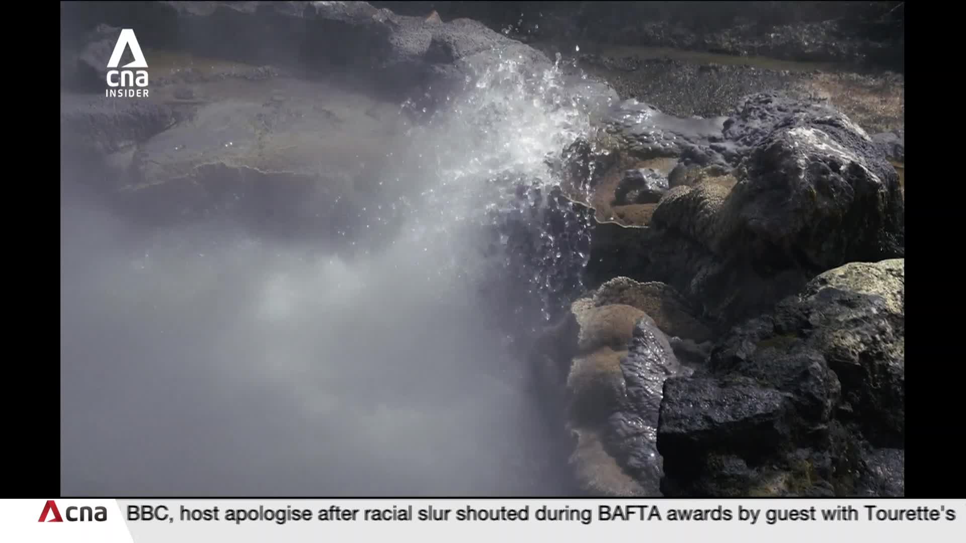 Steam billows from a rocky vent as water erupts upwards. The spray catches the light, a stark contrast to the dark, wet stones surrounding it. Steam billows from a rocky vent as water erupts upwards. The spray catches the light, a stark contrast to the dark, wet stones surrounding it.