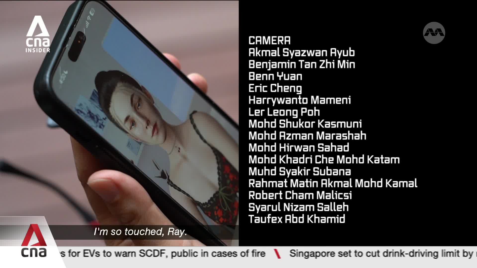 A hand holds a smartphone displaying a woman's face, the screen showing a CNA Insider logo. Text scrolls by on the right, listing names under "CAMERA."