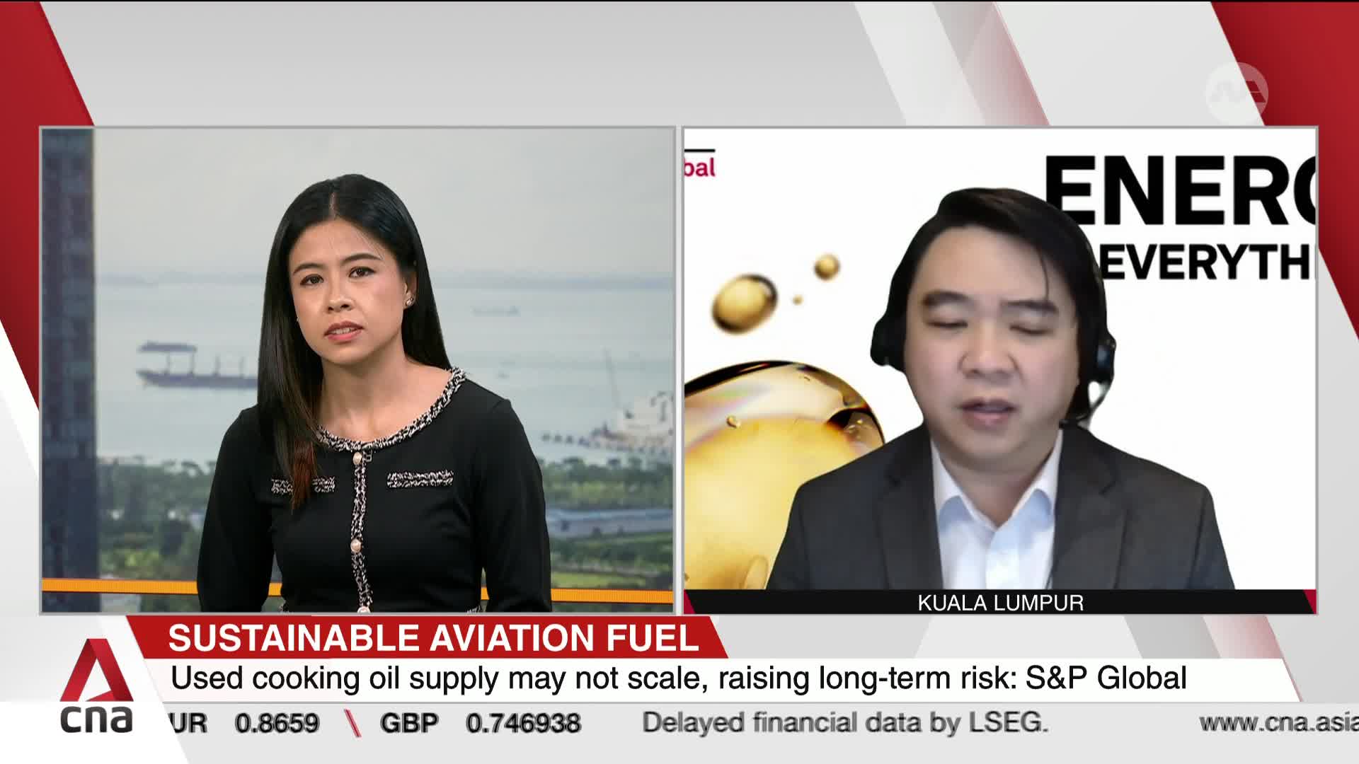 A woman in a black top speaks from Singapore, while a man in a suit appears on a screen from Kuala Lumpur. A graphic behind him shows droplets of golden liquid, and text on the screen discusses sustainable aviation fuel.