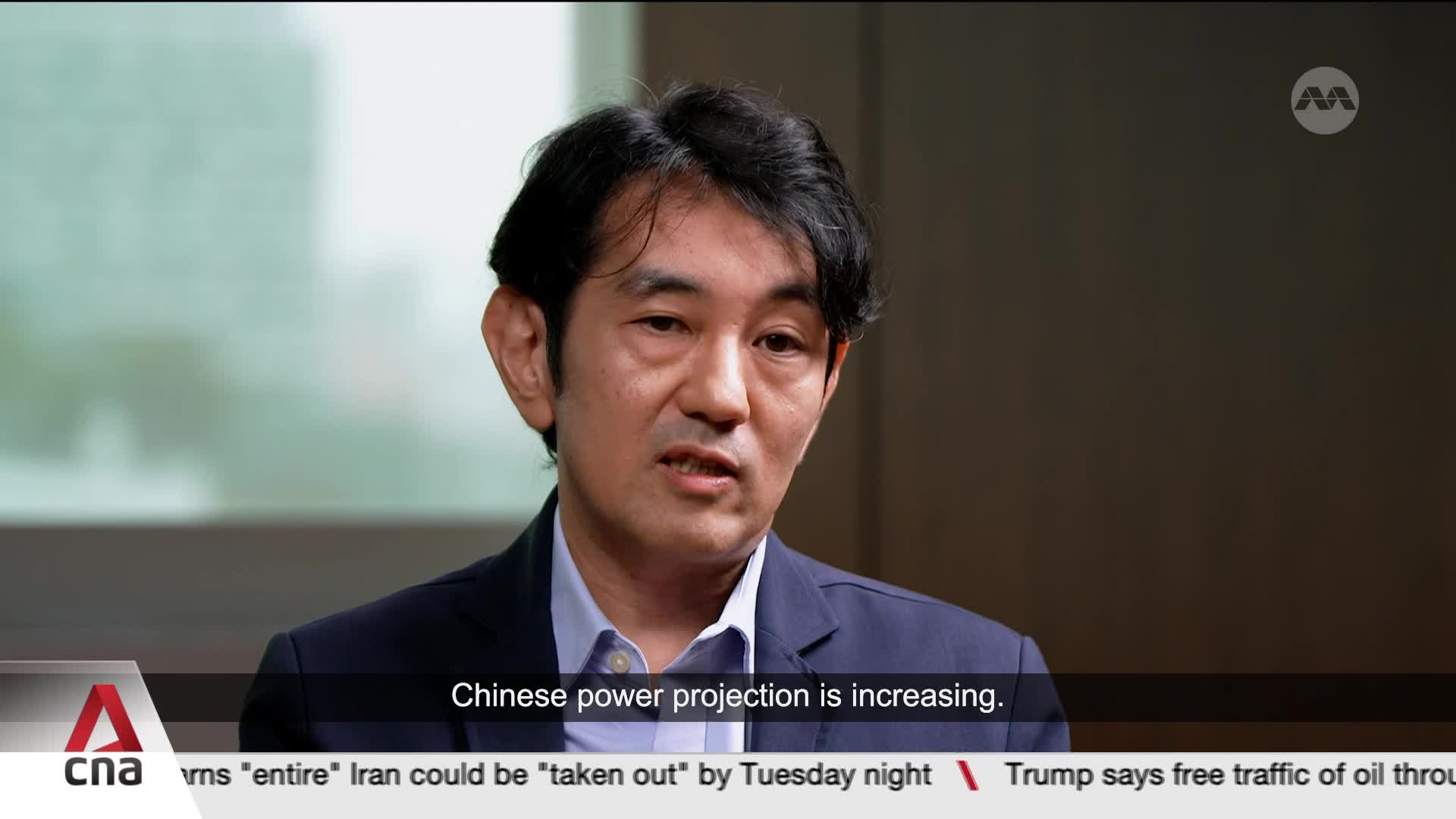 A man in a dark suit speaks directly to the camera, his expression serious. Below him, a ticker displays news headlines, including a report from Singapore's CNA International.