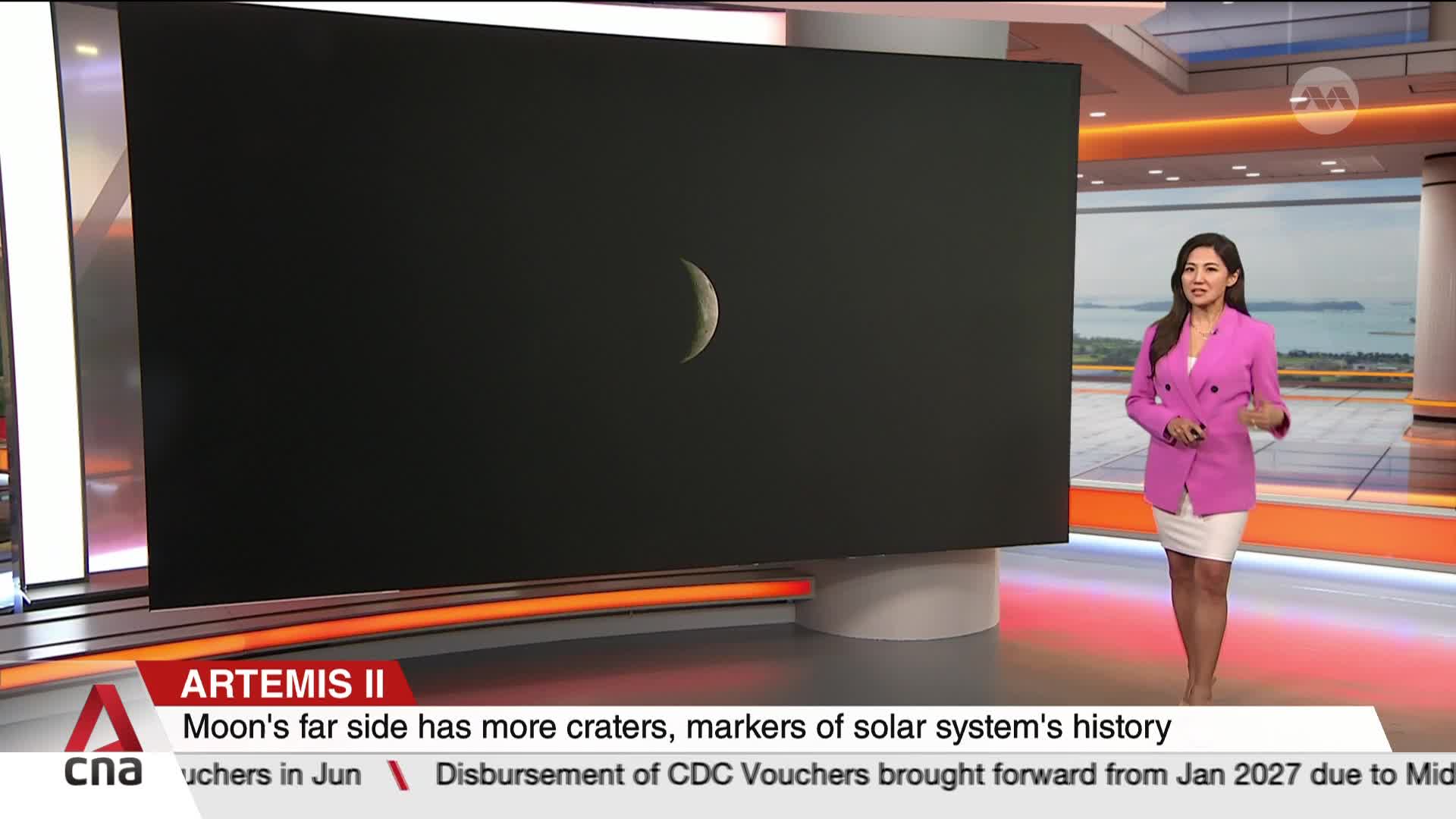 A presenter in a bright pink jacket stands beside a massive screen displaying a crescent moon. The CNA logo and news ticker are visible at the bottom of the frame.