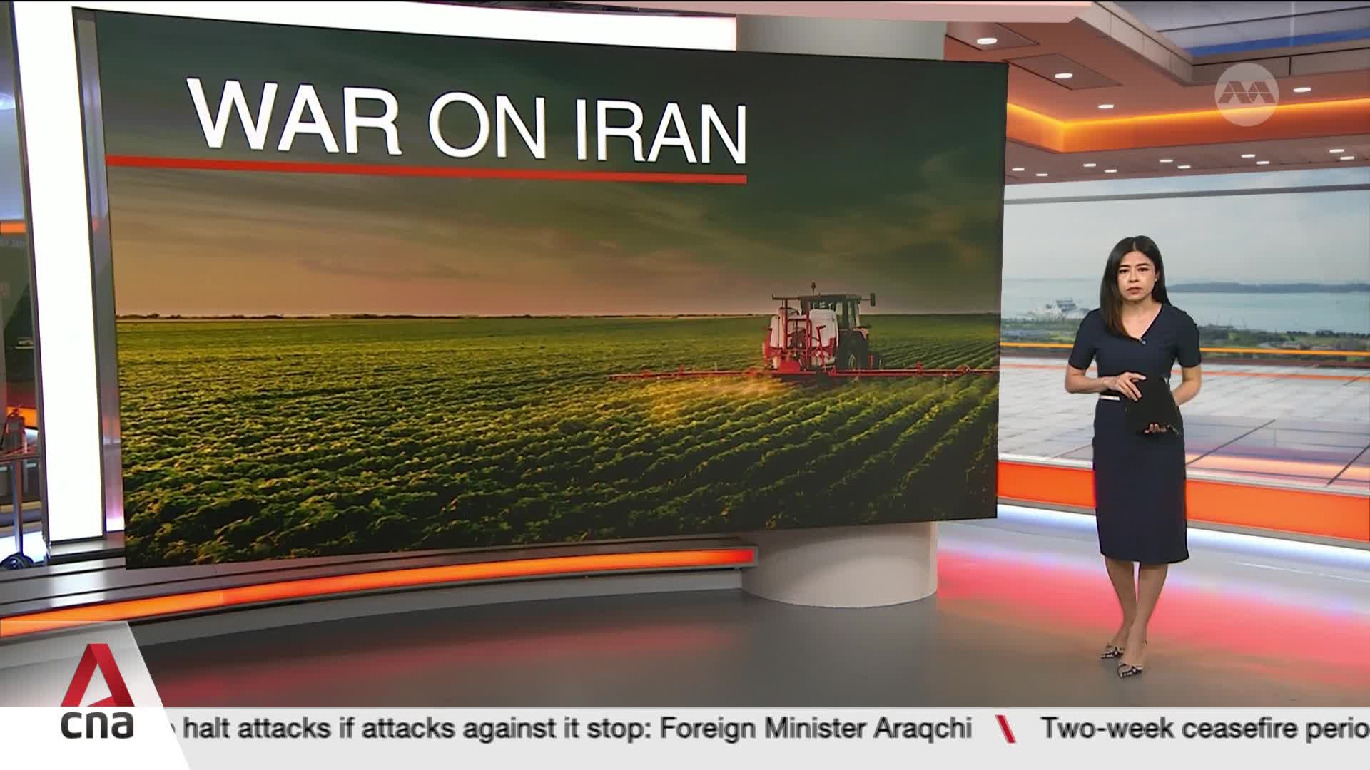A tractor sprays a vibrant green field under a dusky sky, the words "WAR ON IRAN" emblazoned above. A woman in a dark dress stands to the side, holding a tablet.