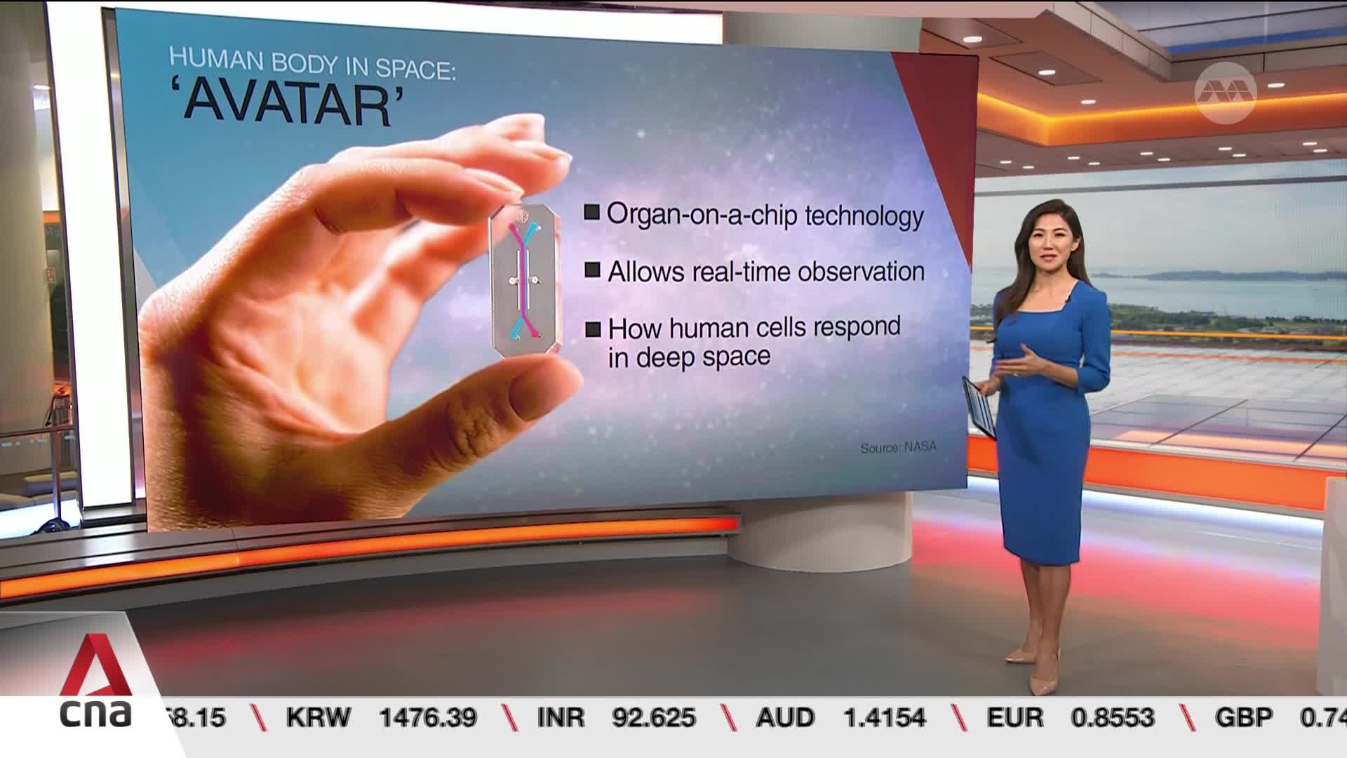 A woman in a blue dress stands beside a large screen displaying information about "Avatar" technology for the human body in space. The screen shows a close-up of a hand holding a small, intricate chip.