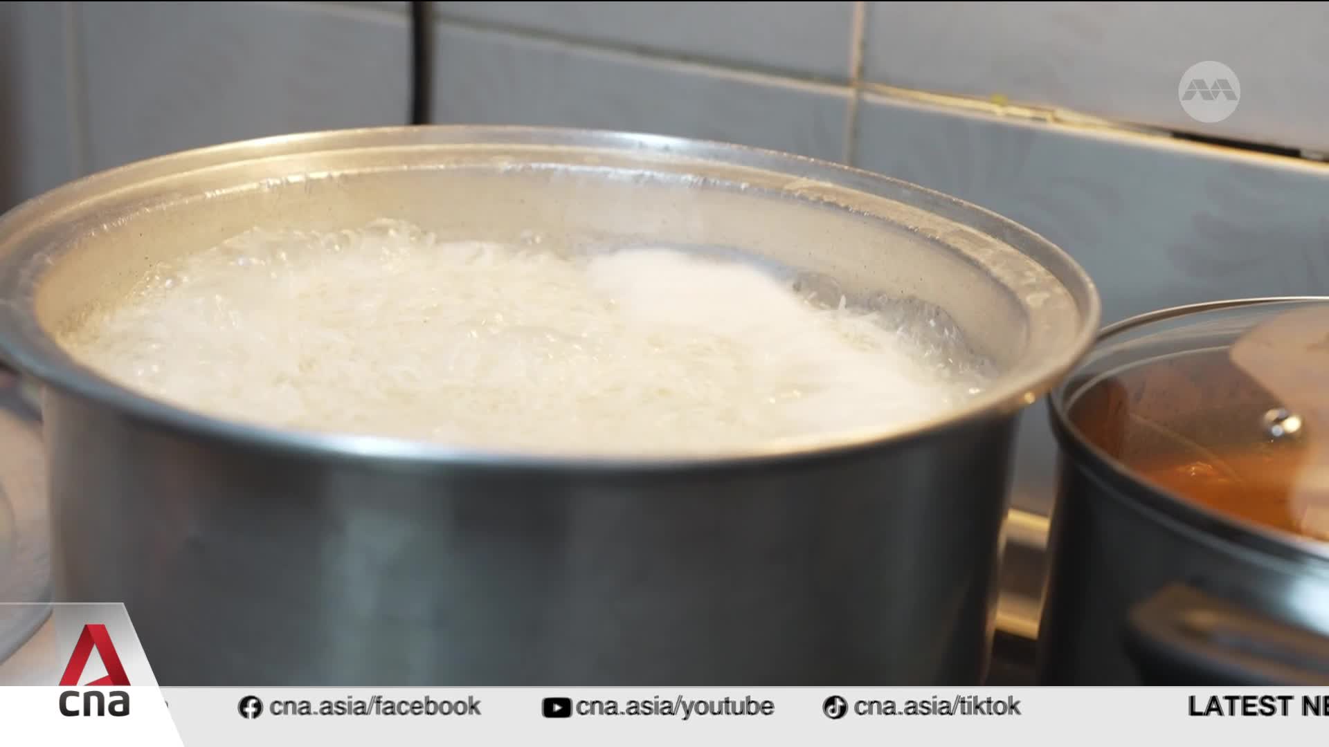 White rice bubbles vigorously in a pot on the stove. Another pot, covered with a glass lid, sits beside it. White rice bubbles vigorously in a pot on the stove. Another pot, covered with a glass lid, sits beside it.