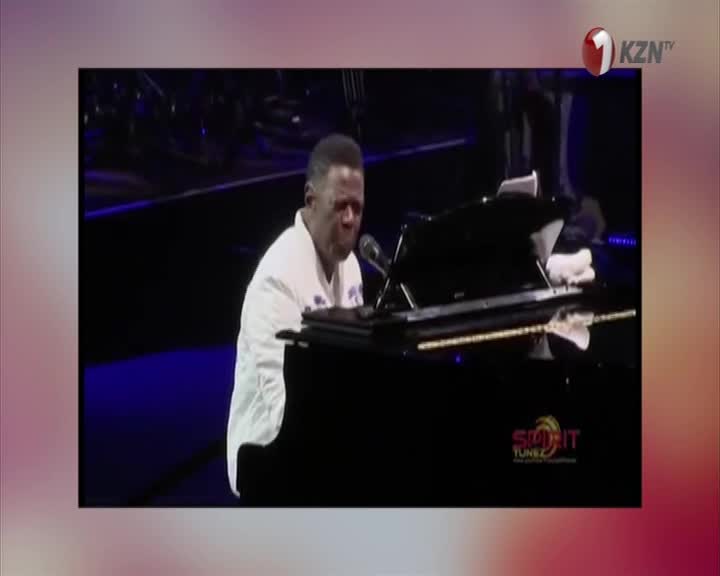 He's at the piano, hands flying over the keys as he sings into the microphone. The 1KZN TV logo sits in the corner, and it's a lively performance.
