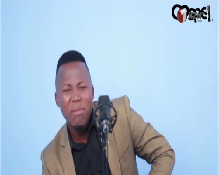 He's singing, his face contorted as he strains into the microphone. The 1KZN TV logo sits in the corner, and he's wearing a tailored jacket.
