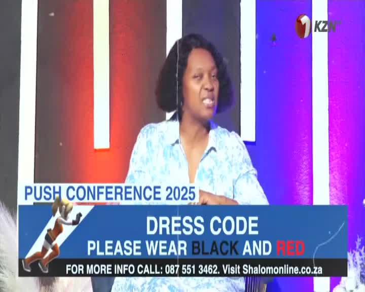 A woman in a floral blouse is speaking on 1KZN TV, with a banner below advertising the "Push Conference 2025" and its dress code. The background is a mix of red and purple, with a white border.
