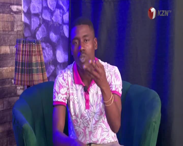 The man in the floral shirt is blowing a kiss toward the camera, his hand cupped near his mouth. The 1KZN TV logo is visible in the corner, and the studio is lit with a blue glow.
The man in the floral shirt is blowing a kiss toward the camera, his hand cupped near his mouth. The 1KZN TV logo is visible in the corner, and the studio is lit with a blue glow.