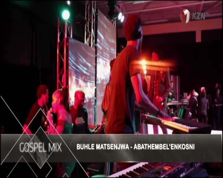 A keyboard player in a black t-shirt is focused on the keys, while a singer with a microphone stands nearby. The 1KZN TV logo is in the corner, and the title "Gospel Mix" is displayed on screen.
A keyboard player in a black t-shirt is focused on the keys, while a singer with a microphone stands nearby. The 1KZN TV logo is in the corner, and the title "Gospel Mix" is displayed on screen.