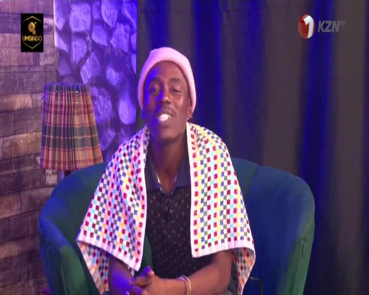 The man in the pink beanie sits on a green chair, a patterned towel draped over his shoulders. He's speaking directly to the camera, likely on 1KZN TV from South Africa.
The man in the pink beanie sits on a green chair, a patterned towel draped over his shoulders. He's speaking directly to the camera, likely on 1KZN TV from South Africa.