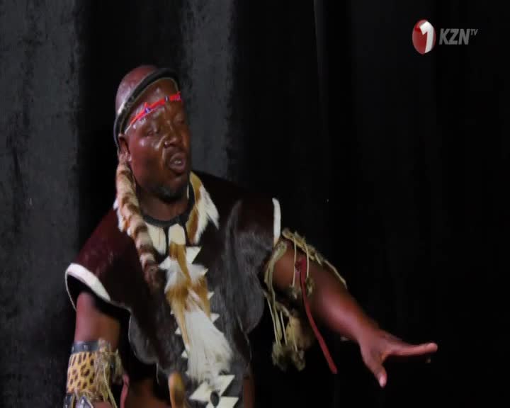 A man in traditional Zulu attire, adorned with animal skins and beads, gestures with his right hand. The 1KZN TV logo appears in the upper right corner. A man in traditional Zulu attire, adorned with animal skins and beads, gestures with his right hand. The 1KZN TV logo appears in the upper right corner.