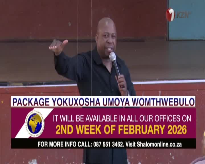 A man in a black shirt speaks into a microphone, gesturing with his left hand. A graphic overlay announces a package available in the second week of February 2026.