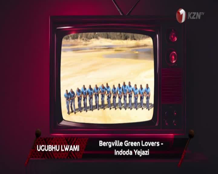A line of men in blue shirts and dark pants stand facing forward on a sandy plain. They are the Bergville Green Lovers, performing "Indoda Yejazi" for 1KZN TV.