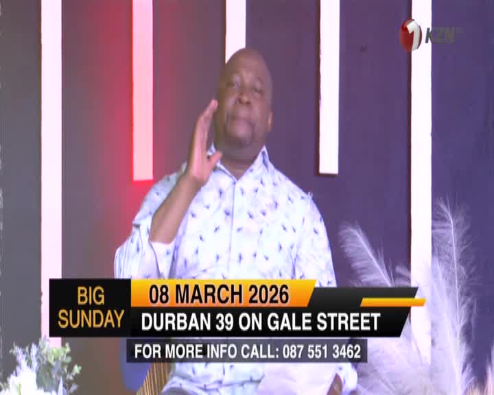 A man in a patterned shirt raises his hand, speaking into a microphone. A graphic overlay announces "BIG SUNDAY" and details for an event in Durban on March 8, 2026. A man in a patterned shirt raises his hand, speaking into a microphone. A graphic overlay announces "BIG SUNDAY" and details for an event in Durban on March 8, 2026.