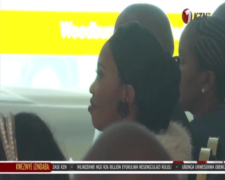 A woman with dark hair in an updo turns her head, her profile sharp against a bright yellow background. The KZN TV logo appears in the upper right corner.
