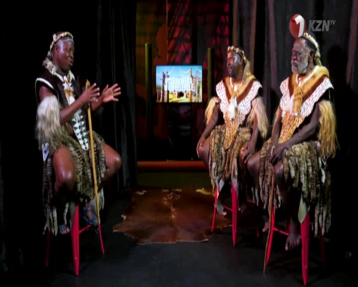 Three men in traditional Zulu attire sit on red stools, engaged in conversation. The KZN TV logo is visible in the upper right corner.