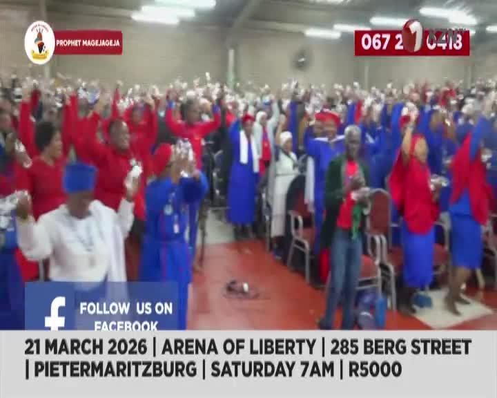 A large crowd, many in vibrant blue and red attire, raises their hands in unison. The energy is palpable as they gather for an event at the Arena of Liberty in Pietermaritzburg.