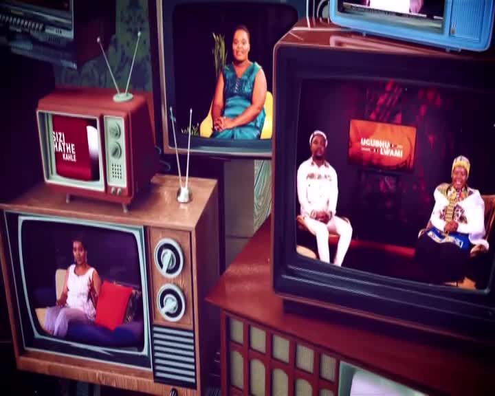 A woman in a teal dress sits on a stool in a studio, her image displayed on an old television. Another screen shows two men, one in white, the other in traditional attire, seated on couches. The 1KZN TV logo, "UGUSHO LAMI," flashes briefly. A woman in a teal dress sits on a stool in a studio, her image displayed on an old television. Another screen shows two men, one in white, the other in traditional attire, seated on couches. The 1KZN TV logo, "UGUSHO LAMI," flashes briefly.