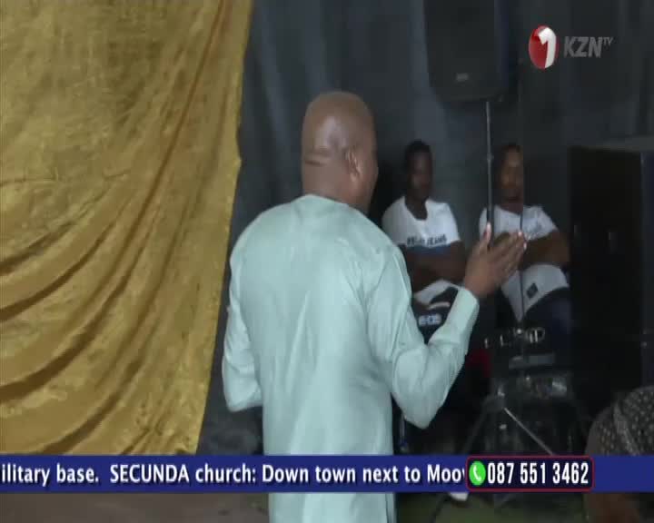 A man in a light green shirt gestures with his hands as he speaks to an audience in Secunda. The KZN TV logo is visible in the corner.