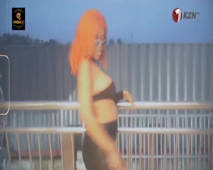 A woman with bright orange hair moves with a sway of her hips. The KZN TV logo is visible in the upper right corner.