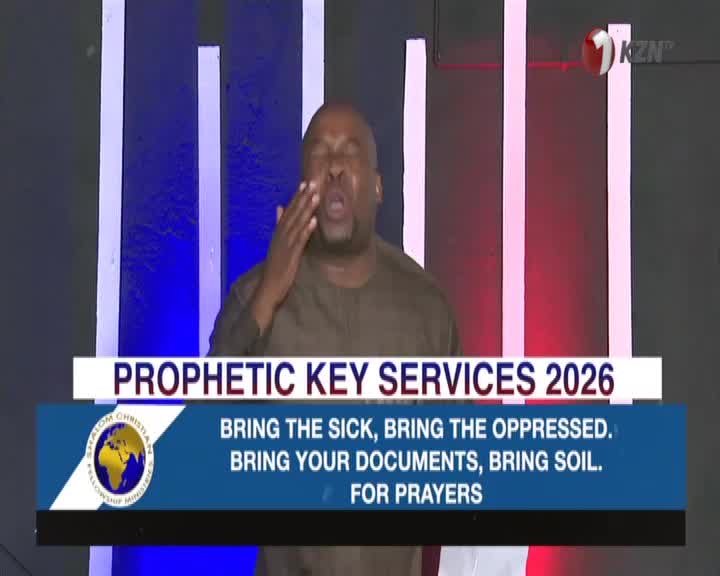 A man in a brown shirt is speaking with his eyes closed, hand raised to his face. A graphic behind him announces "Prophetic Key Services 2026" and invites attendees to "Bring the sick, bring the oppressed. Bring your documents, bring soil. For prayers."