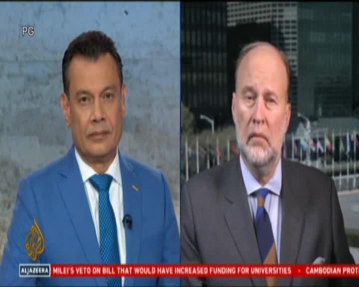 Two men in suits stare directly ahead, framed in separate sections of a split screen. The Al Jazeera logo is visible on the lower left, while a news ticker scrolls across the bottom.
