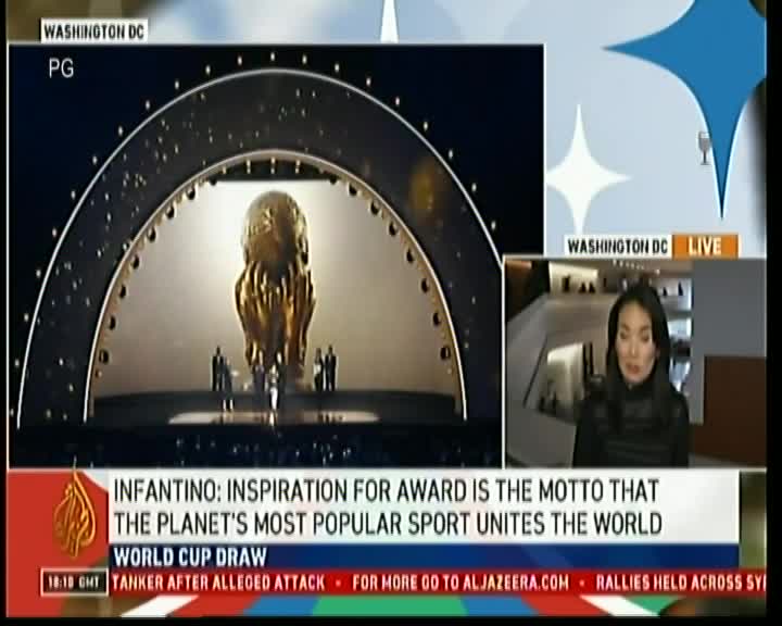 A golden trophy sits center stage under a large, arched structure, while a news anchor in Washington D.C. reports live on Al Jazeera. The World Cup draw is the focus, with a headline about Infantino's inspiration for the award.
A golden trophy sits center stage under a large, arched structure, while a news anchor in Washington D.C. reports live on Al Jazeera. The World Cup draw is the focus, with a headline about Infantino's inspiration for the award.