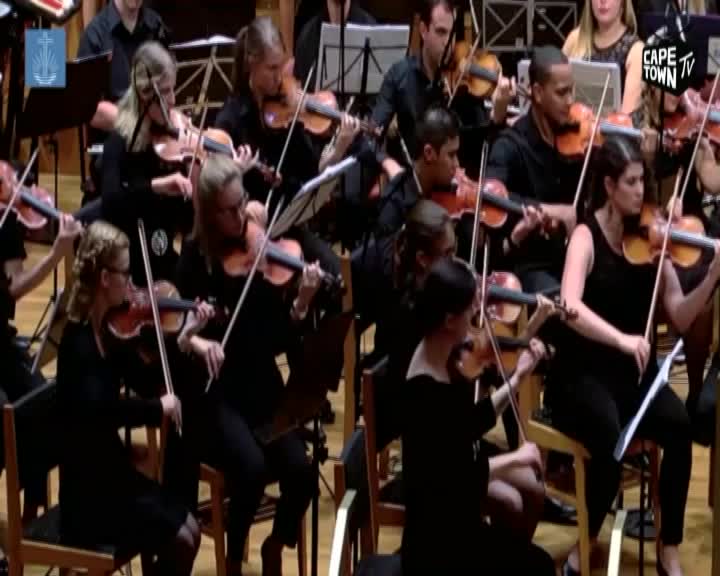 Violins sing out as the orchestra performs, their bows moving in unison. A Cape Town TV logo appears in the corner, marking the broadcast.