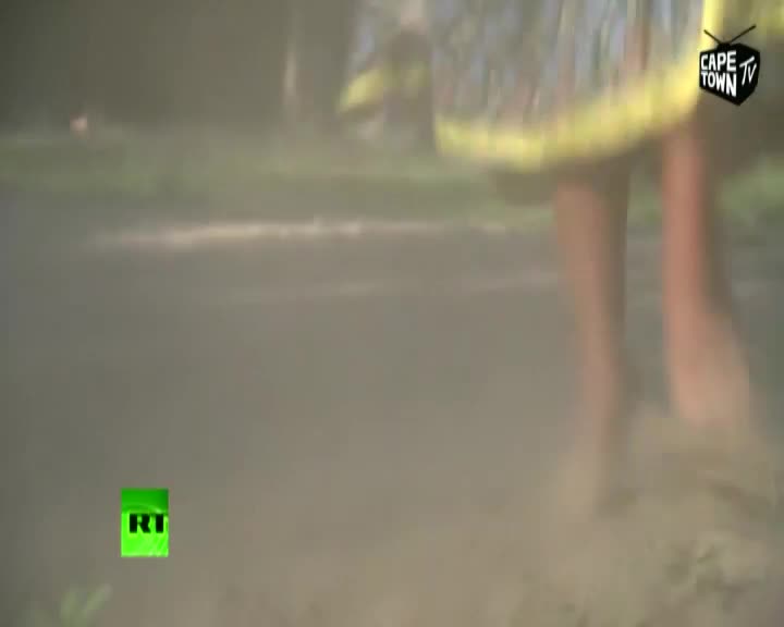 Dust billows up as bare feet pound the earth, the hem of a patterned dress flaring with each stride. The Cape Town TV logo is visible in the corner. Dust billows up as bare feet pound the earth, the hem of a patterned dress flaring with each stride. The Cape Town TV logo is visible in the corner.