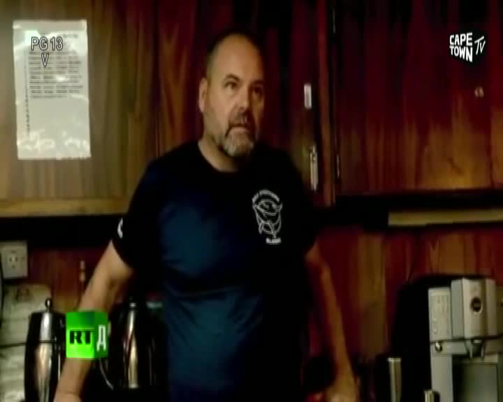 A man with a beard stands in front of a wooden wall, wearing a dark t-shirt. A Cape Town TV logo appears in the upper right corner of the screen.