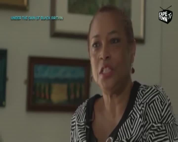 A woman with short, dark hair speaks directly to the camera, her expression earnest. Behind her, framed artworks hang on a pale wall, one featuring a stylized landscape. A Cape Town TV logo appears in the upper right corner.