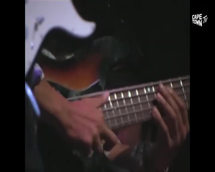 Fingers dance across the fretboard of a sunburst bass guitar. The Cape Town TV logo appears in the corner.