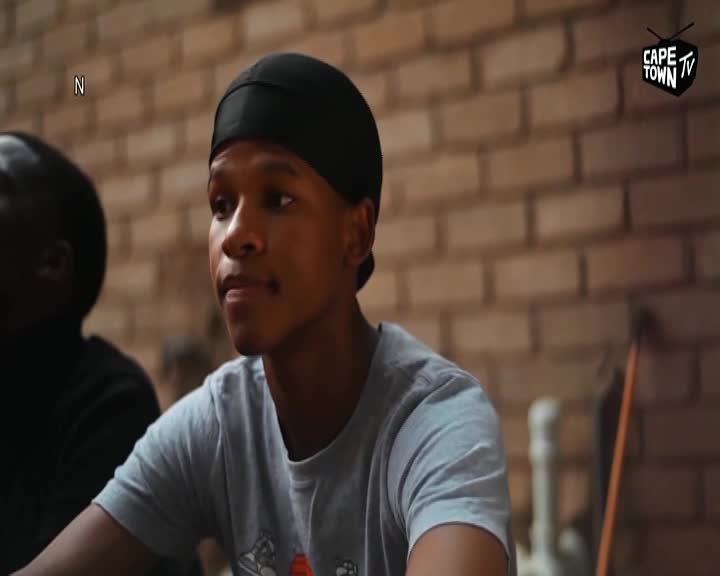 A young man, wearing a black durag and a grey t-shirt, looks intently to his left. The Cape Town TV logo is visible in the upper right corner.