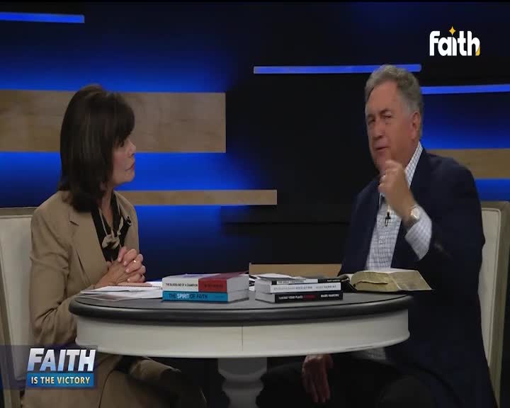 On the Faith TV set, a man in a navy blazer gestures thoughtfully, his hand near his chin. Across the table, a woman in a tan jacket listens intently, while a stack of books and an open Bible sit between them.
