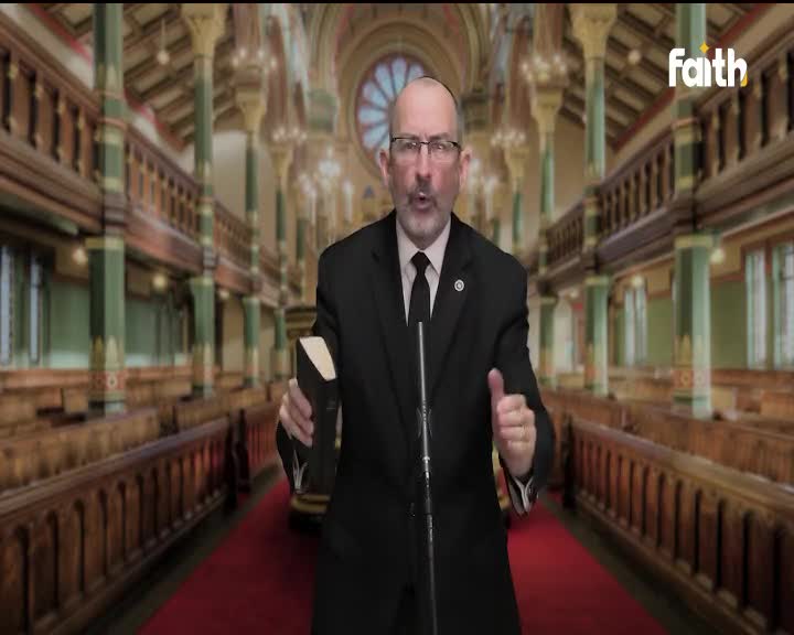 A man in a suit stands before a microphone, holding a book and gesturing with his hands. Behind him, a digitally rendered church interior serves as the backdrop for what looks like a broadcast on Faith TV.
