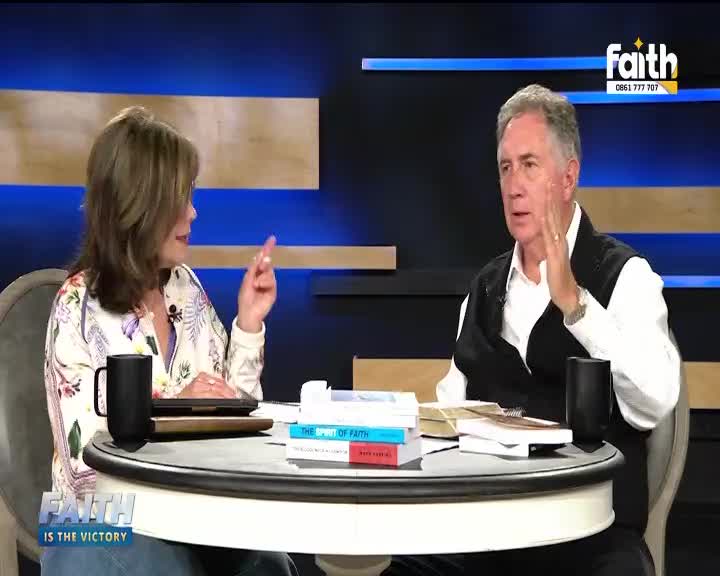 On the set of Faith TV in South Africa, a man gestures with his hand raised, while the woman across from him points with her finger. Books and mugs sit on the table between them.
