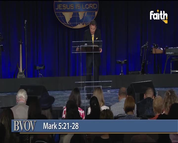 A man in a suit, reading from a lectern, speaks to a seated audience in what looks like a studio. The Faith TV logo is visible, and the broadcast is likely from South Africa.
