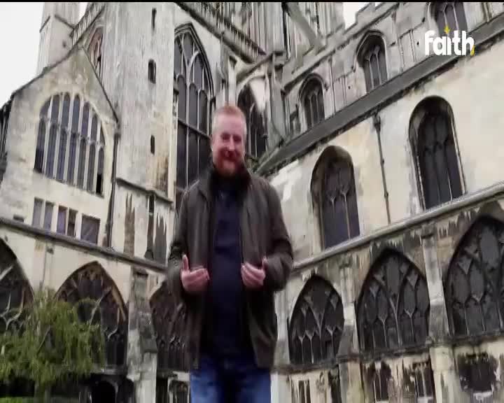 A man stands before a weathered stone building, gesturing with his hands as if he's speaking to someone. The Faith TV logo is visible in the corner, suggesting a broadcast from South Africa.
