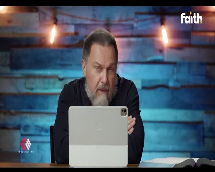 The man leans forward, his gaze fixed on the tablet before him. A Bible lies open to his right, its pages illuminated by soft light.