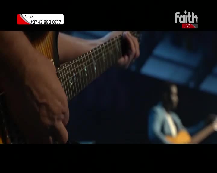 A man's hands are on the fretboard of a guitar, fingers pressing down on the strings. In the background, another man plays an acoustic guitar, his face obscured by shadow. The Faith TV logo is visible in the corner, with a South African contact number.